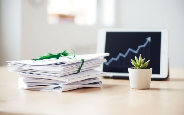 Soft-focus image showing documents, a thriving plant, and a graph, symbolizing how to get approved for an SBA loan.