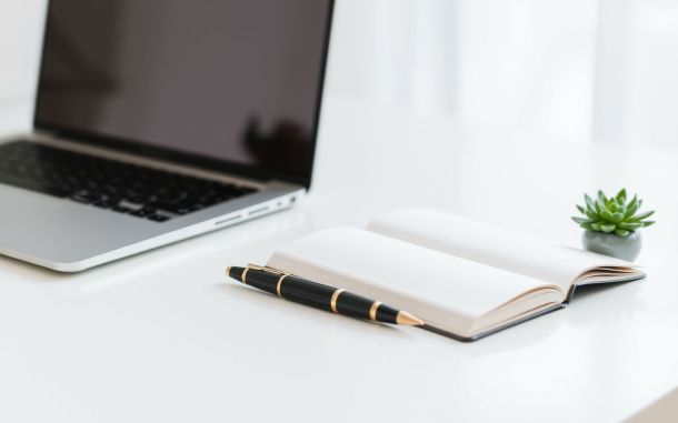 Desk setup with laptop and notebook, symbolizing how to find high paying freelance writing jobs.