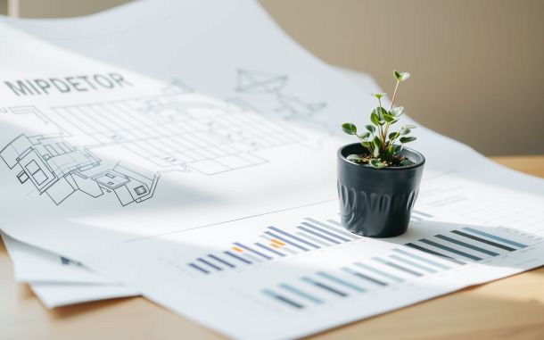 Real estate investment strategies concept with blueprints, charts, and a plant.