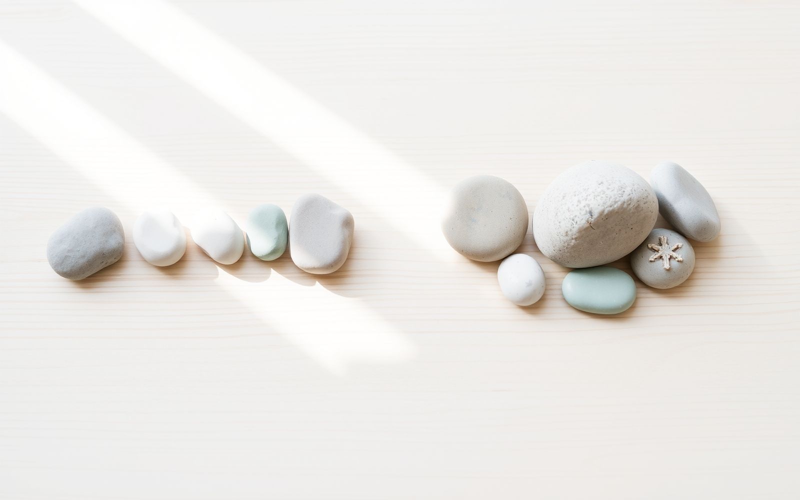 Comparing debt snowball vs avalanche methods using arrangements of pastel stones on a bright surface.