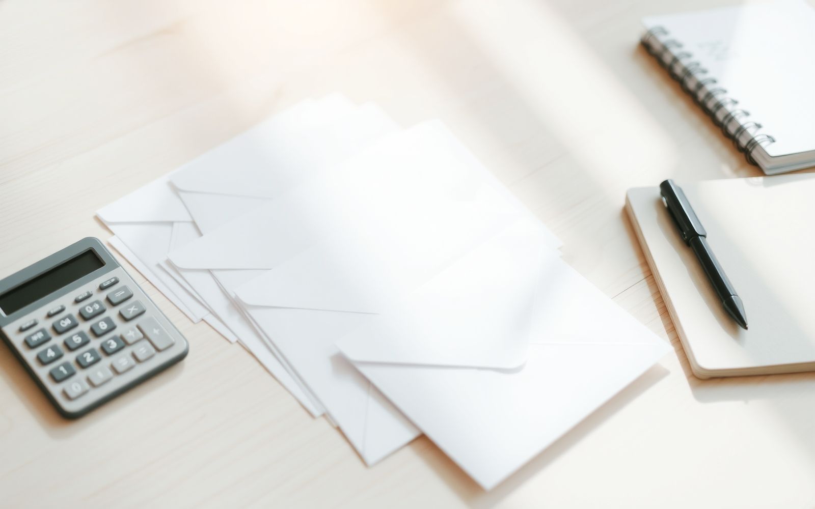Neatly arranged paper envelopes, calculator, and notebook representing the envelope budgeting system on a bright surface.